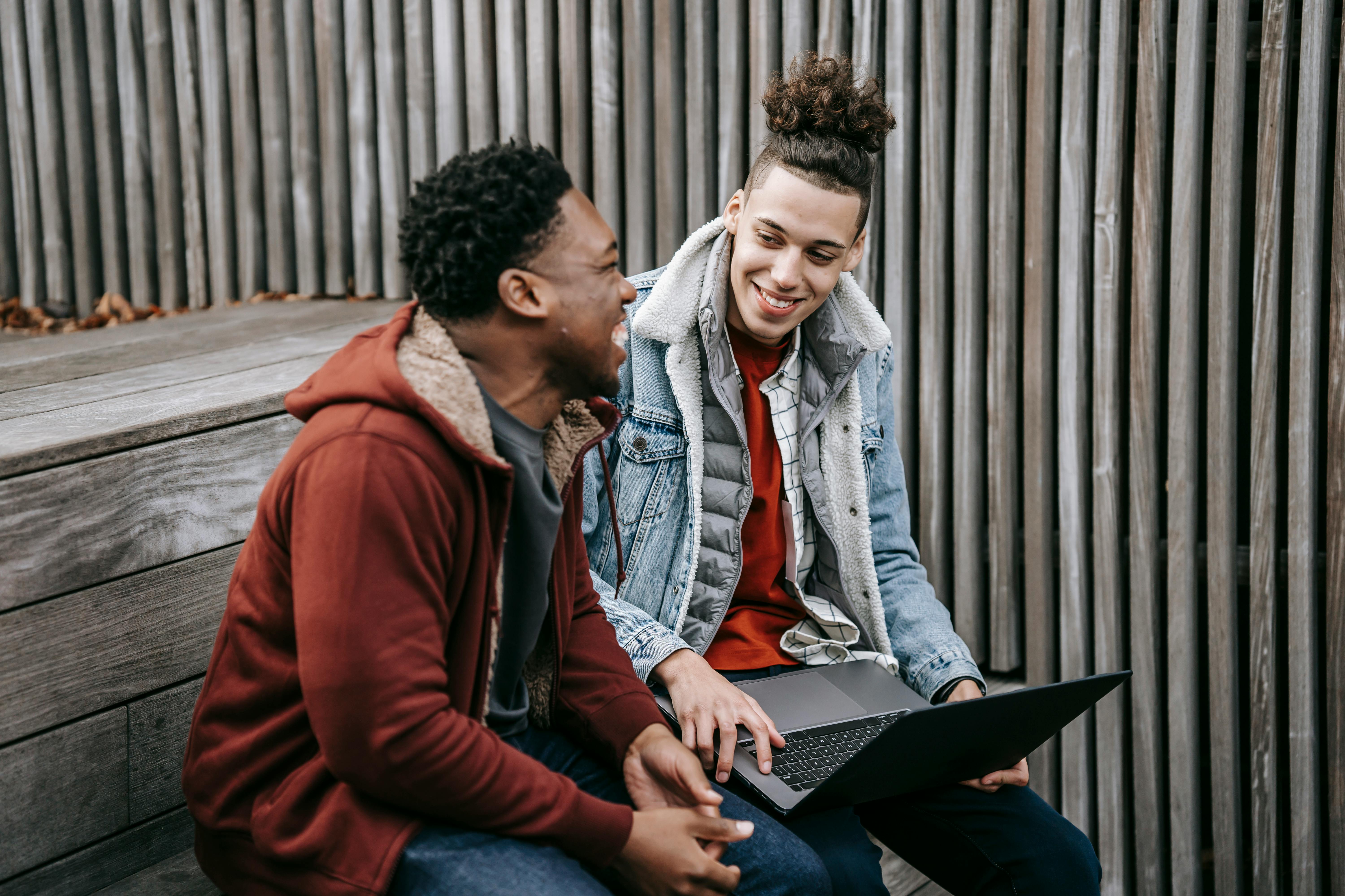 happy multiethnic friends smiling while browsing laptop